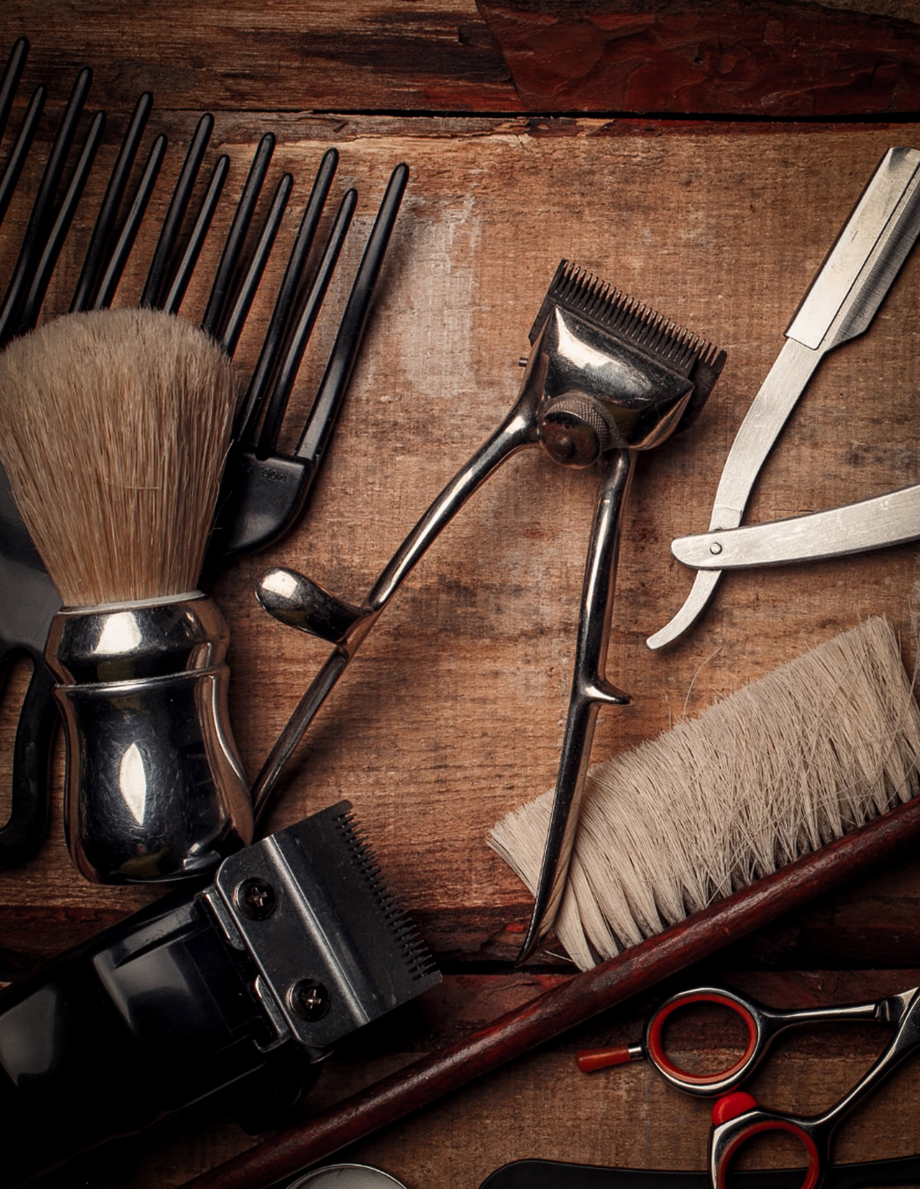 Traditional barber tools including a shaving brush and straight razor on a wooden bench