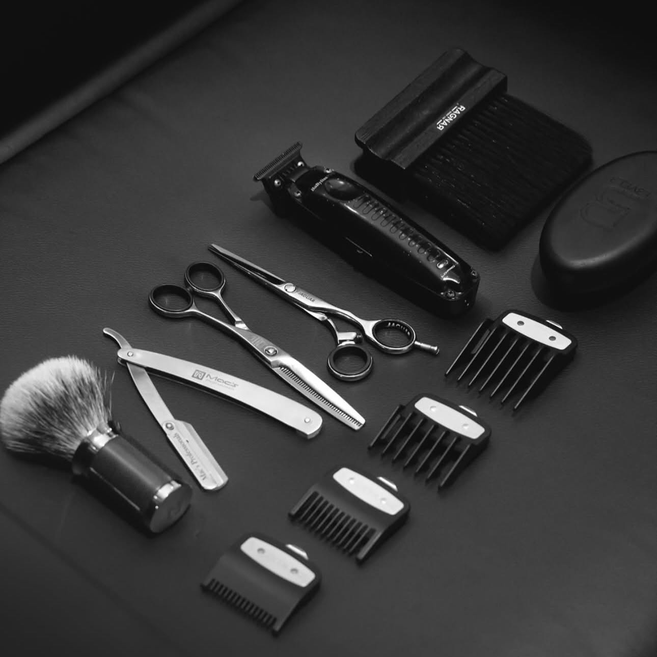 Barber tools laid out including clippers, scissors and a straight razor